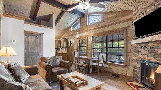 A rustic interior with a fireplace, wooden furniture, and a stone accent wall. - Table Rock Lakeside cabin -Ticket Deals & Resort Perks included! (Branson)