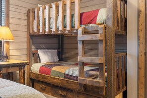 A bunk bed with a wooden frame, a quilted bedspread, and a small bedside table with a lamp. - Lakeside 2bd/2ba cabin, sleeps 6. Free Use of Kayaks-Ticket DEALS and Resort Perks!! (Branson)