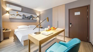 Habitación de hotel con cama, escritorio, silla, obras de arte y una puerta.