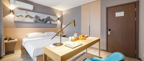 Habitación de hotel con cama, escritorio, silla, obras de arte y una puerta.