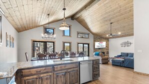A spacious kitchen with a large island, wooden ceiling, and multiple windows. - Spacious Family Retreat | Free Boat Slip + Show Tickets (Branson)