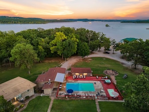 A residential property with a swimming pool, outdoor seating, and a view of a lake.