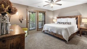 A bedroom with a bed, a ceiling fan, a nightstand, a lamp, a dresser, a vase with dried flowers, and a dreamcatcher on the wall. - Lakefront Condo, Private Deck, Sleeps 12. 4 bedroom, 3 Bathroom.  2 miles from Siilver Dollar City (Branson)