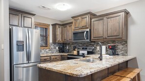 A modern kitchen with stainless steel appliances, wooden cabinets, and a granite countertop. - Lakefront Condo, Private Deck, Sleeps 12. 4 bedroom, 3 Bathroom.  2 miles from Siilver Dollar City (Branson)