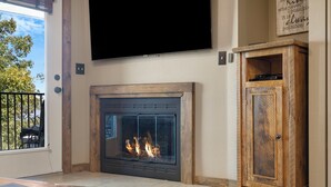 Una sala de estar con chimenea, un televisor montado encima y un mueble de madera.