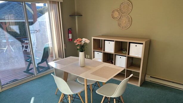 Une pièce comprenant une table et des chaises, une bibliothèque, un vase avec des fleurs et un extincteur.