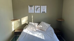 Une chambre à coucher avec un lit, deux tables de chevet et un mur orné de trois œuvres d’art encadrées.