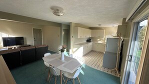 Un espace de vie compact comprenant un coin repas, une kitchenette et un téléviseur.