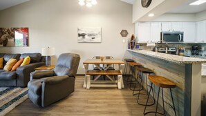 Ein modernes Wohnzimmer mit einer Couch, einem Esstisch und einer Küchenzeile inklusive Mikrowelle.