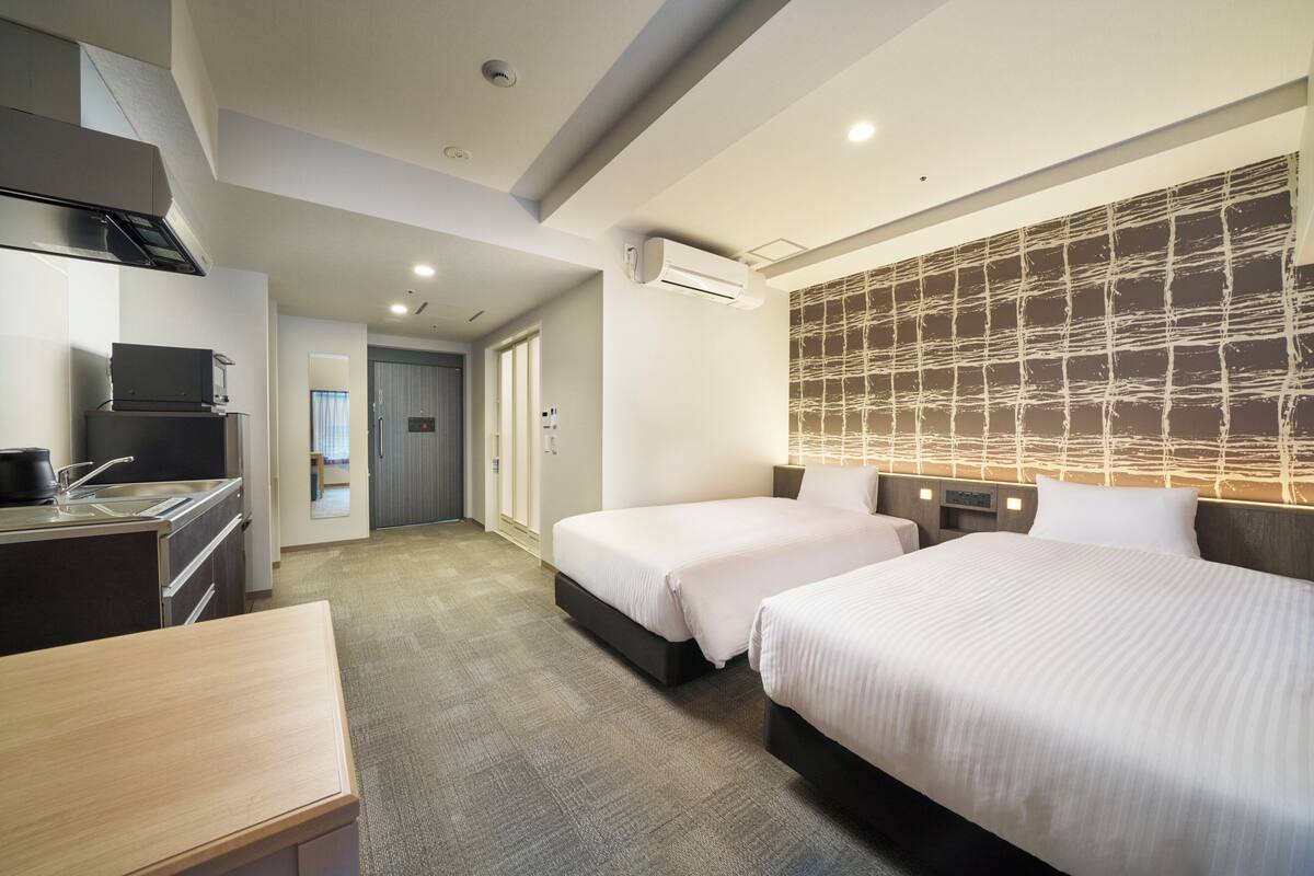 Ein Hotelzimmer mit zwei Betten, einer Küchenzeile und einem Badezimmer.