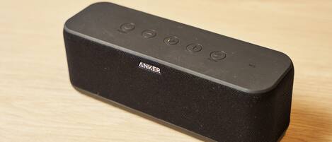 Un altavoz portátil negro con textura de tela y el nombre de la marca visible en el lateral.