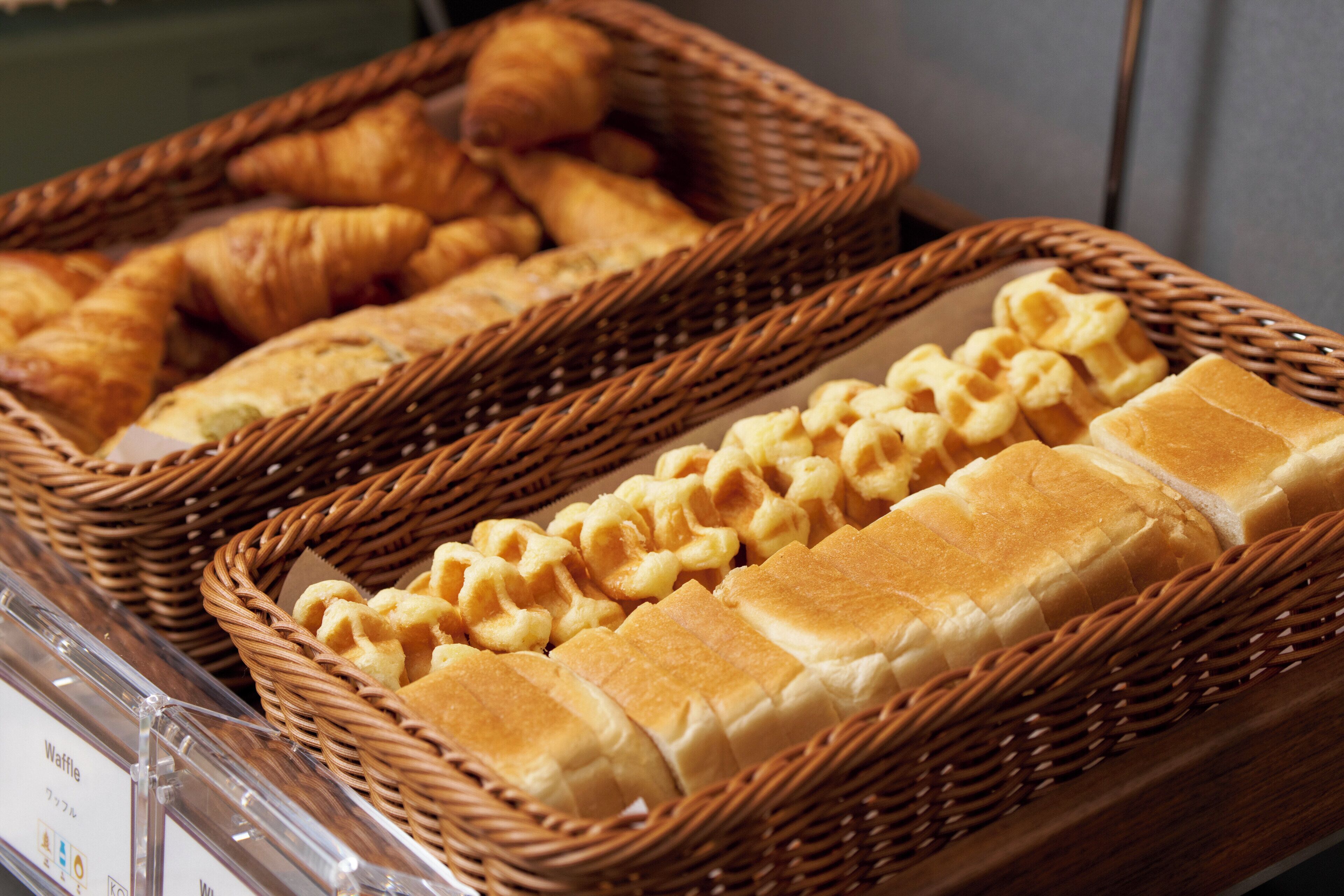 Une variété de produits de boulangerie, notamment des croissants et des gaufres, présentés dans des paniers en osier.