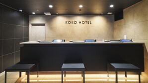 A reception desk at Koko Hotel with a modern design, featuring a flat surface and three seating areas in front. - KOKO HOTEL Osaka Namba Sennichimae (Osaka)
