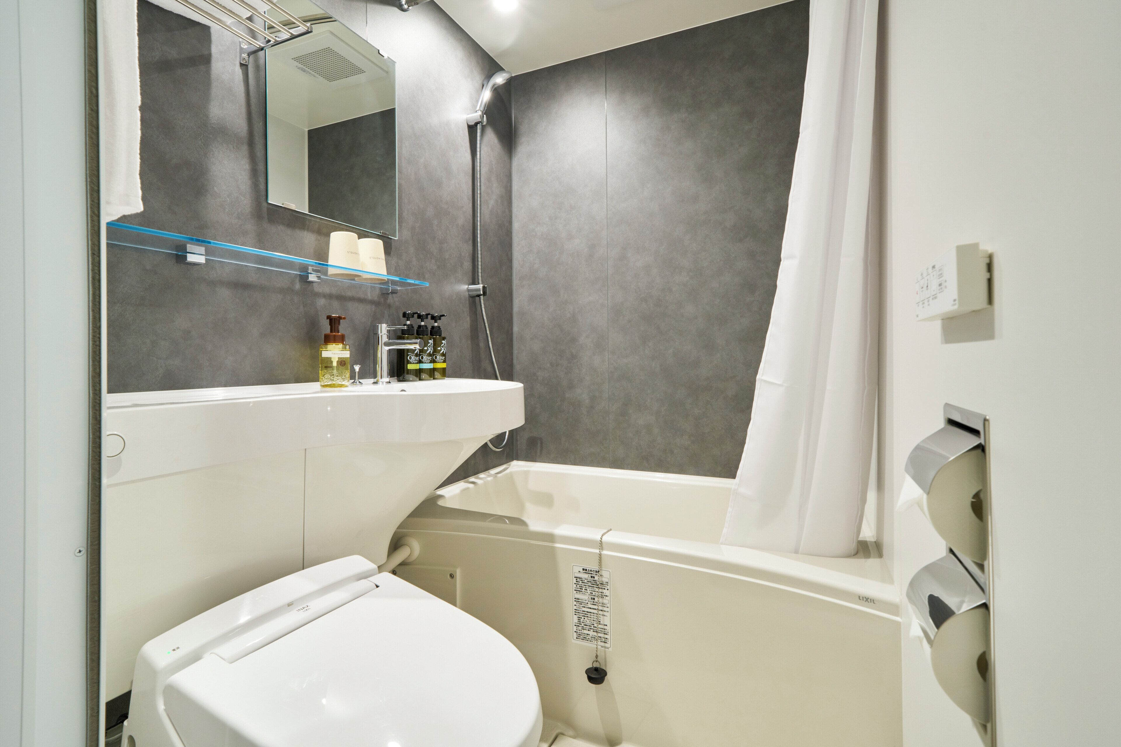 Ein modernes Badezimmer mit Badewanne, Toilette, Waschbecken und Spiegel.