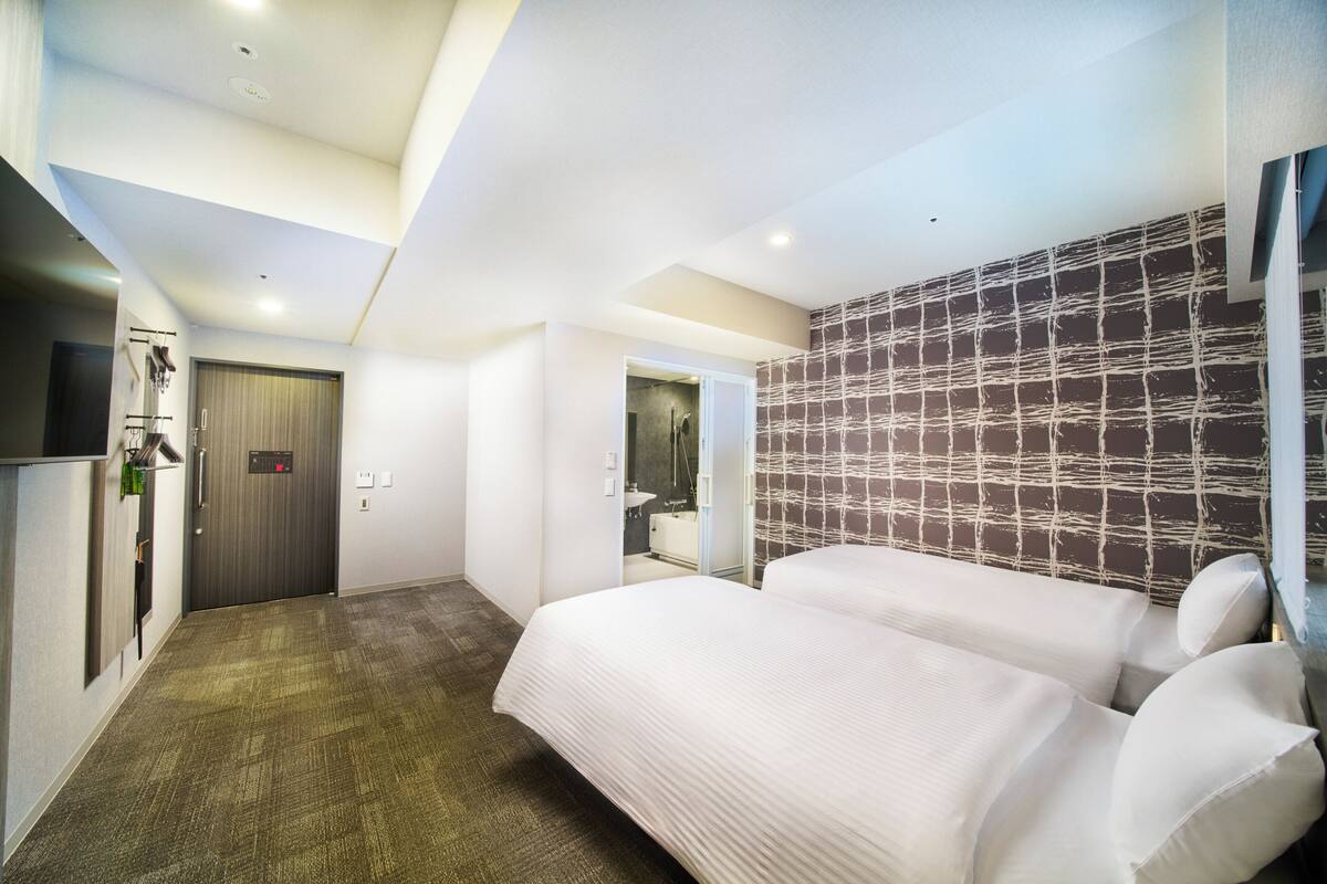 Ein Hotelzimmer mit einem großen Bett, einem Kleiderschrank, einem Spiegel und einer Duschkabine.
