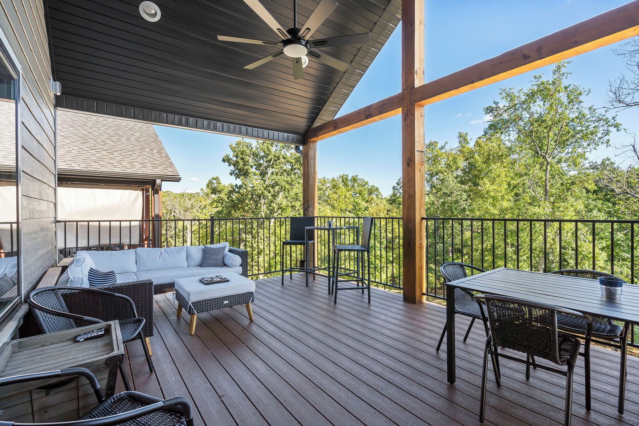 Une terrasse extérieure couverte, dotée d’un ventilateur de plafond, d’un canapé, d’une table et de chaises.