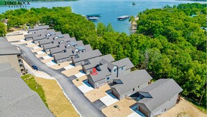 Une rangée de chalets de plain-pied, avec un quai s’avançant dans un lac, le tout entouré d’une forêt dense.