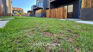 A modern building with a flat roof, large windows, and a grassy courtyard.