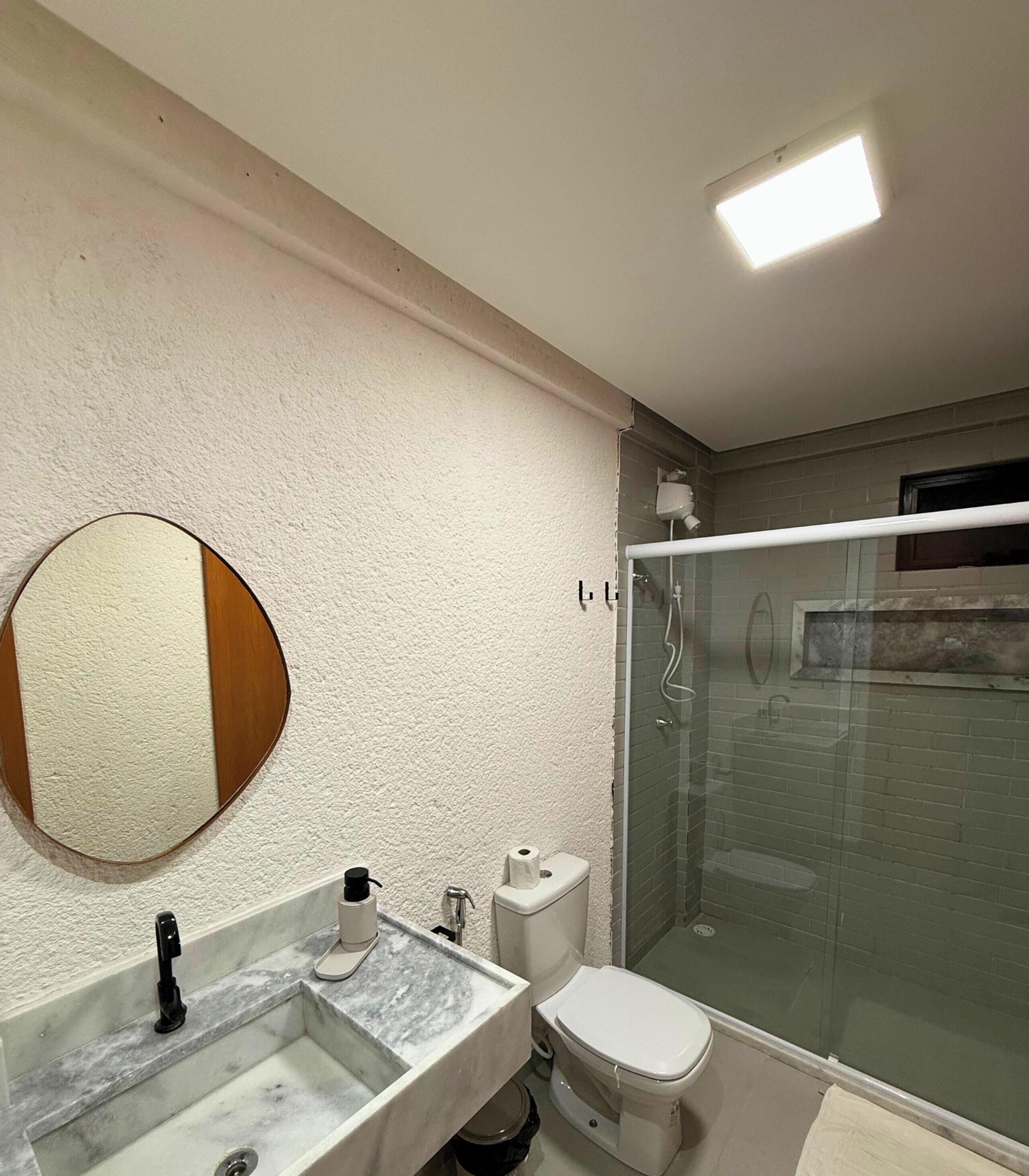 A bathroom with a marble sink, toilet, and glass-enclosed shower.