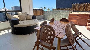 A modern outdoor patio with a dining table, chairs, a sofa, and a view of the cityscape.