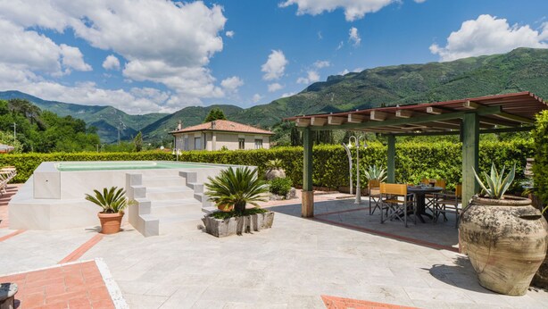 Un patio con piscina, mobiliario exterior y vistas a montañas.