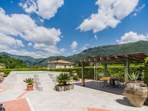 A patio area with a pool, outdoor seating, and a view of mountains. - Versilia by Interhome (Camaiore)