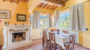 Un comedor con chimenea, vigas de madera en el techo y vistas a las montañas.