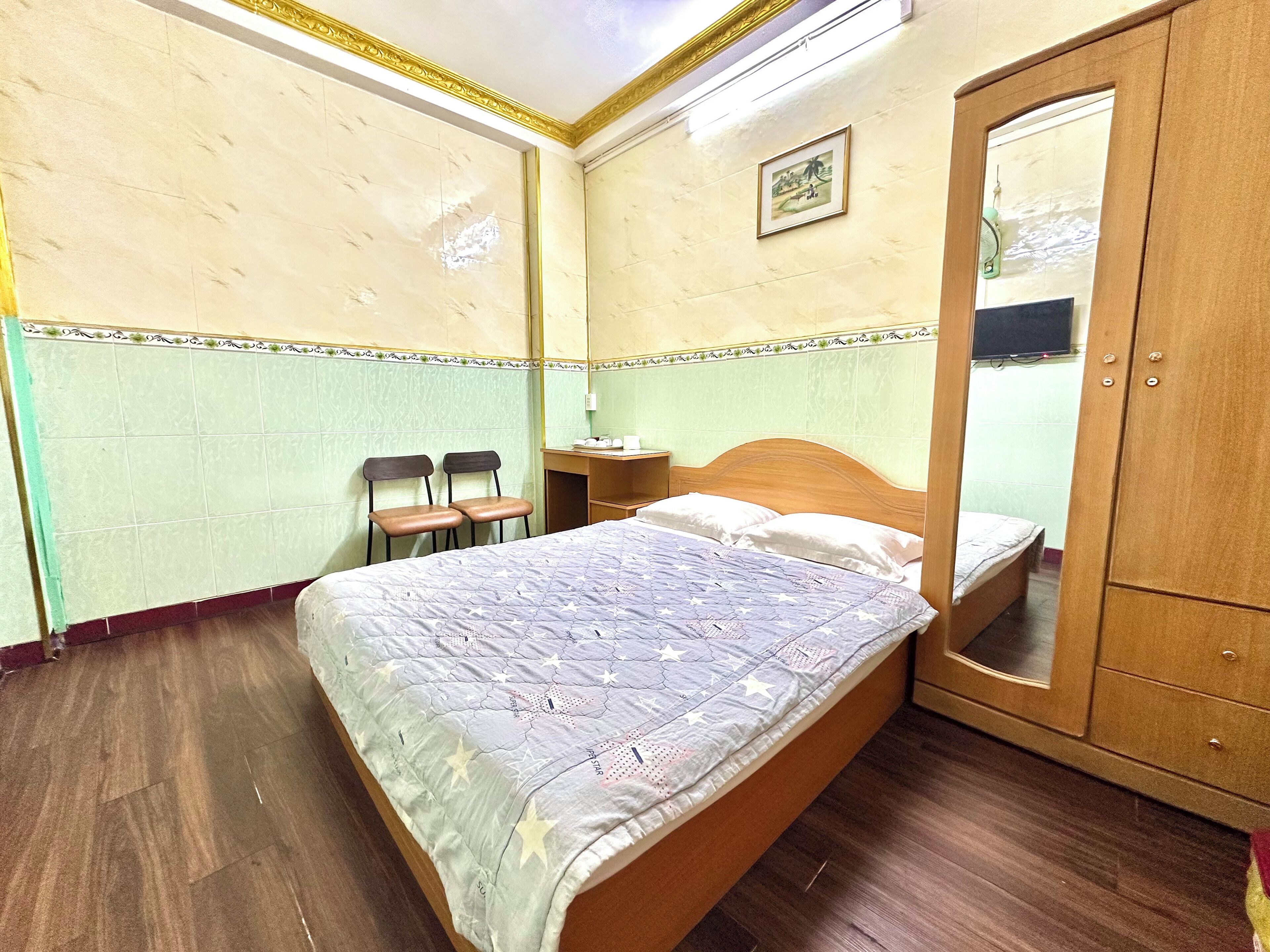 Une chambre à coucher avec un lit, une armoire en bois, un bureau avec une chaise et une petite table.