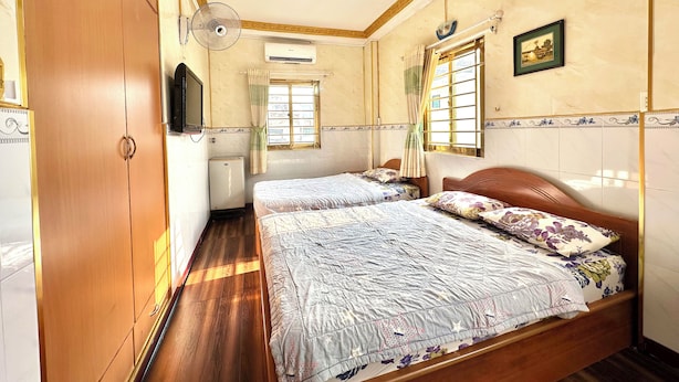 Une chambre avec deux lits, une armoire, un téléviseur et une fenêtre avec des rideaux.