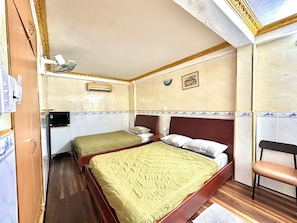 Een kleine hotelkamer met twee éénpersoonsbedden, een bureau, een stoel en een televisie.