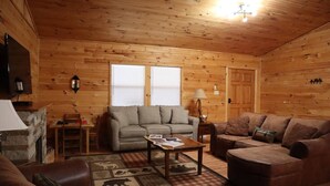 A cozy log cabin interior with a sofa, a coffee table, and a fireplace. - Laurel Lodge-Devil`s Bathtub/Nat Tunnel (DUFFIELD)