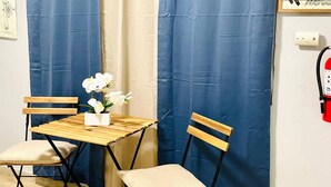 A room with a wooden table and two chairs, a blue curtain, and a wall-mounted fire extinguisher. - Eco-friendly Mountain Retreat Near Beaches (Ceiba)