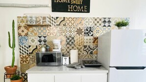 Uma cozinha com painel decorativo, micro-ondas, máquina de café e geladeira.