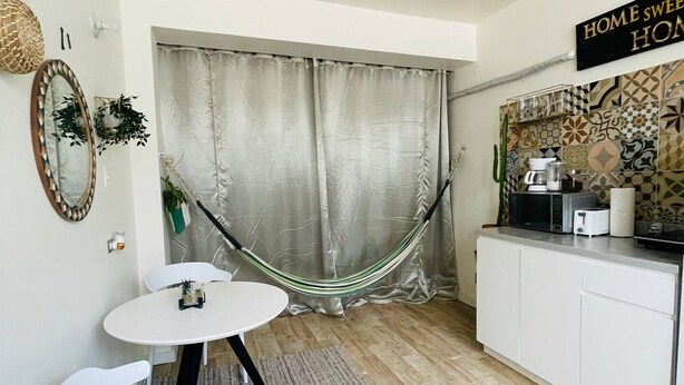 Cozinha compacta com área de refeições, uma rede e uma placa com a inscrição 'Lar doce lar'.