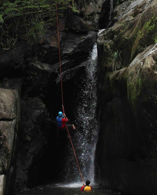 Uma pessoa fazendo rapel em uma cascata rochosa.