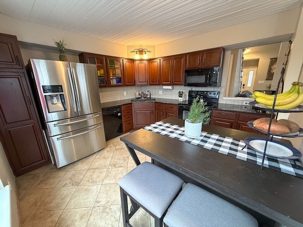 A modern kitchen with stainless steel appliances, wooden cabinets, and a central island with seating.