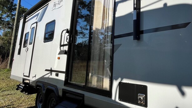A white RV with a sliding door and a small window. - Cozy RV in Palm Bay, FL with pool access! (Palm Bay)