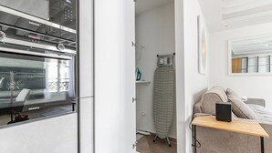 Une cuisine moderne équipée d'un four Siemens, d'une petite planche à repasser et d'un canapé dans un espace de vie compact.
