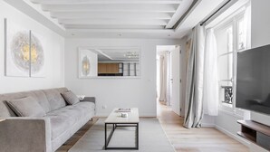 Un salon moderne avec un canapé gris, une table basse et un téléviseur posé sur un meuble.