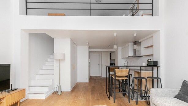 A modern apartment with a living room, dining area, kitchen, and staircase. - Blueground | Le Marais, elev & w/d, nr Pompidou (Paris)