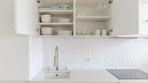 A kitchen with white cabinets, a stainless steel sink, and a tiled backsplash. - Blueground | Le Marais, elev & w/d, nr Pompidou (Paris)