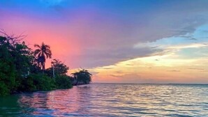 A calm body of water reflecting a sunset with a distant shoreline. - Hotel Martin  (Corozal)