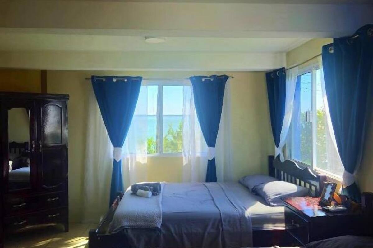 Ein Schlafzimmer mit einem Bett, einem Schminktisch und einem Fenster mit Vorhängen.
