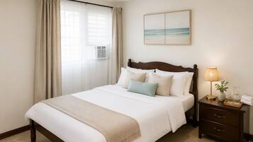 Quarto de hotel com cama, mesa de cabeceira com abajur, vaso com planta e pintura na parede.