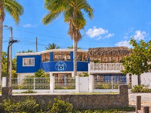 A blue building with a palm tree and a thatched-roof structure, labeled 'Hotel Martin.' - Hotel Martin (Corozal)