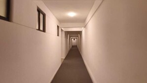 Ein schmaler, gut beleuchteter Flur mit weißen Wänden und einem dunklen Teppich.