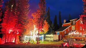 Une grande maison dotée d’une terrasse et d’un espace extérieur couvert, entourée d’arbres aux feuilles d’automne.