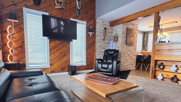 Un salon moderne avec un canapé en cuir, un téléviseur à écran plat et un mur décoratif en pierre.