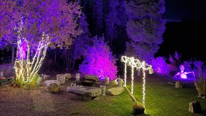 Une scène nocturne en plein air, avec des arbres illuminés, une décoration en forme d’étoile et une figurine de squelette.