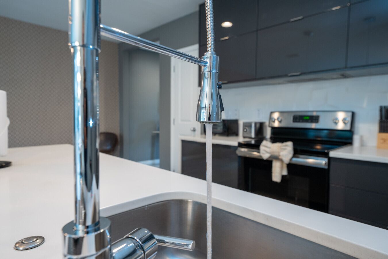 A modern kitchen with a stainless steel sink, a faucet, and a microwave in the background.